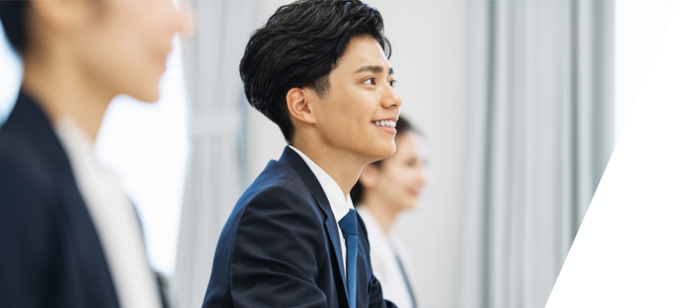 スーツを着用した人が椅子に座っている笑っている写真